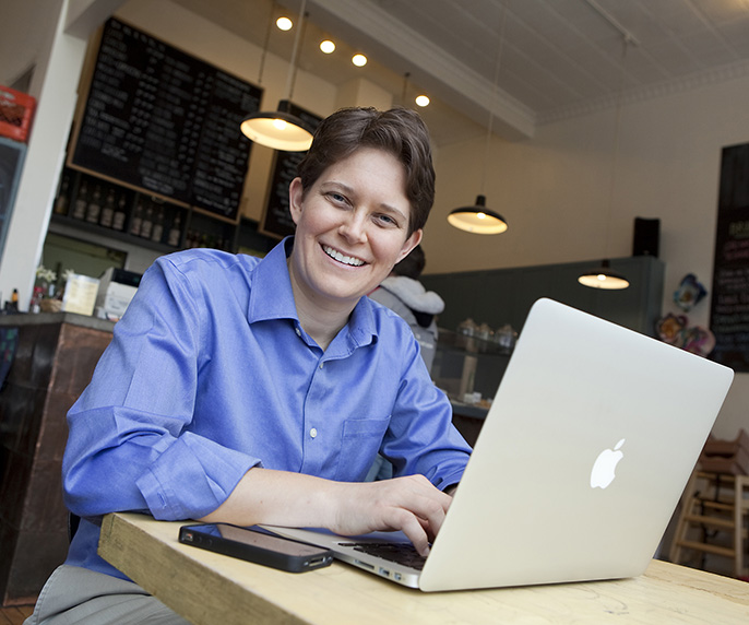 A photo of Dorie Clark with a Mac computer